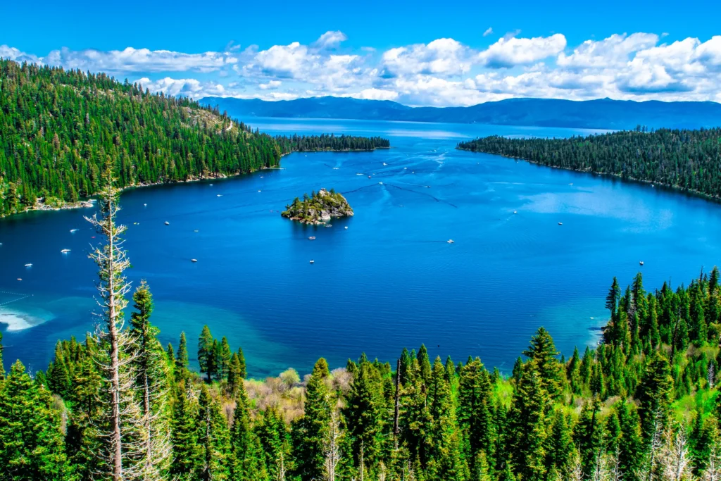 Aerial view of Emerald Bay at Lake Tahoe surrounded by pine forest, with a small island in the center and mountains in the distance